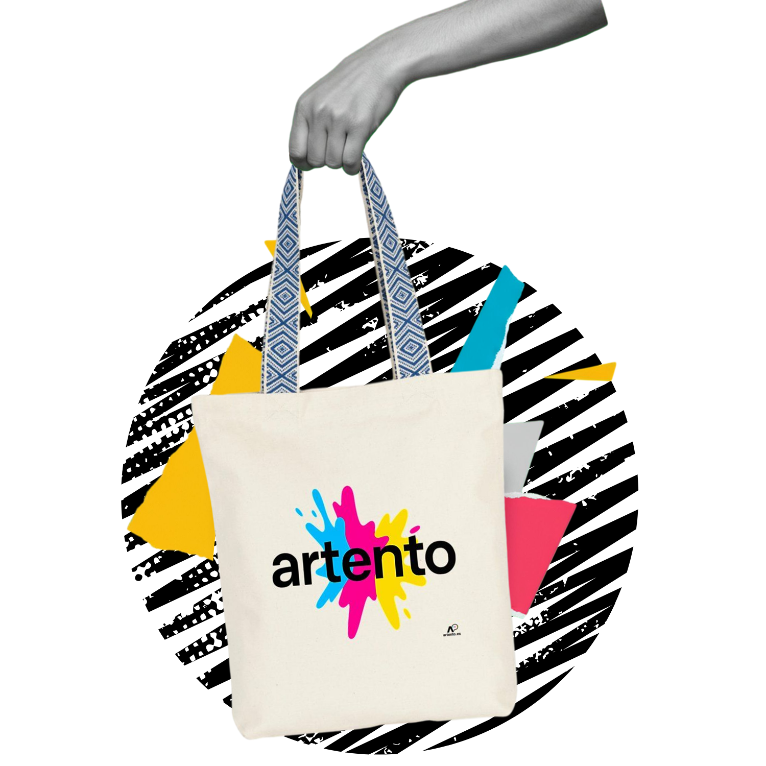 A beige tote bag with blue ethnic-patterned straps and the word “artento” in bold black over cyan, magenta, and yellow paint splashes, held by a grayscale hand against a black background with colorful geometric shapes.